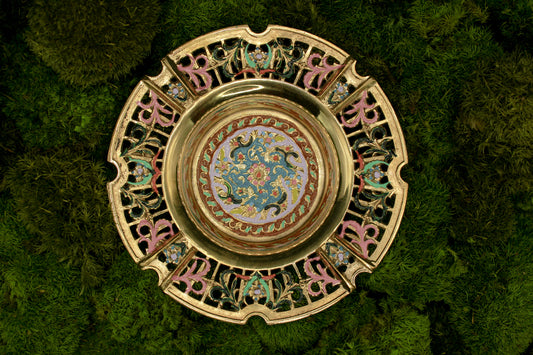 Decorative brass vintage ashtray with intricate painted designs on a green textured background