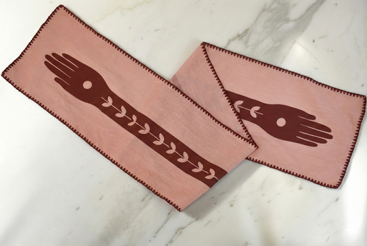 Pink table runner with hand designs on a marble surface
